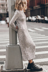 Woman leaning against a pole in a silver sequined midi dress with long bell sleeves and black combat boots.