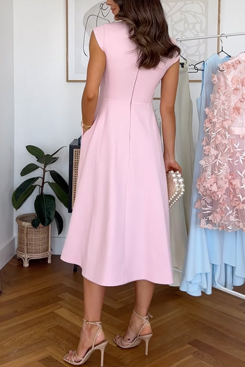 Woman wearing a pink midi dress with cap sleeves, a pleated skirt, and a ruffle detail on the shoulder, holding a pearl clutch and wearing beige strappy heels.