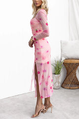 Side view of a woman in a pink floral mesh dress with a ruched bodice and thigh-high slit