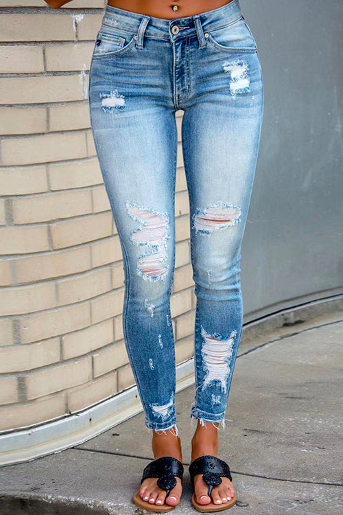woman wearing light blue ripped skinny jeans with frayed hem and black sandals
