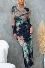 Close-up of a woman in a long-sleeved, abstract print midi dress, leaning against a concrete wall.