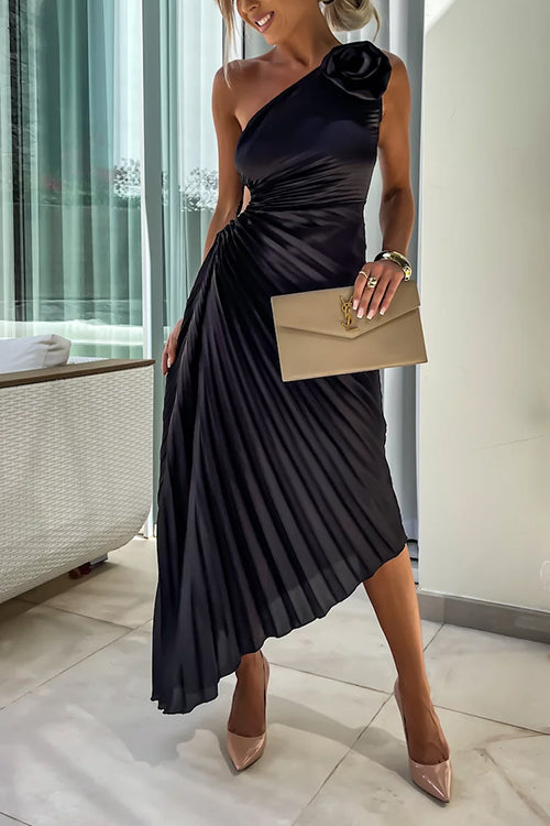 Woman wearing a black one-shoulder pleated dress with a floral embellishment and a clutch