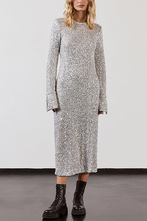 Woman standing against a white wall in a silver sequined midi dress with long sleeves and black combat boots.
