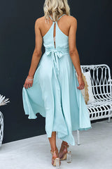 Woman wearing a light blue high-low midi dress with an open back and tie detail, turning to the side.