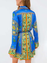 Back view of a woman wearing a blue shirt dress with a colorful floral pattern.