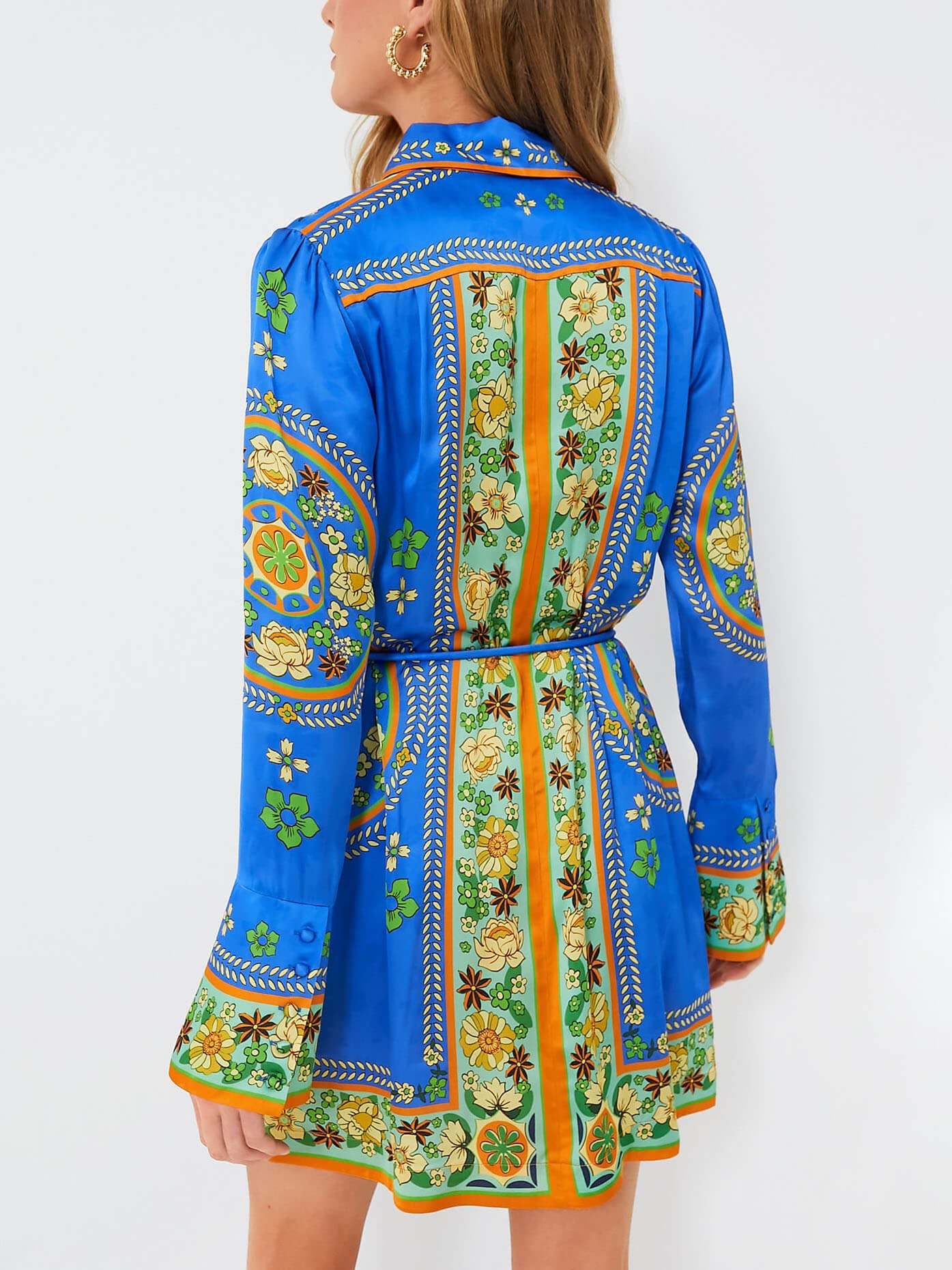 Back view of a woman wearing a blue shirt dress with a colorful floral pattern.