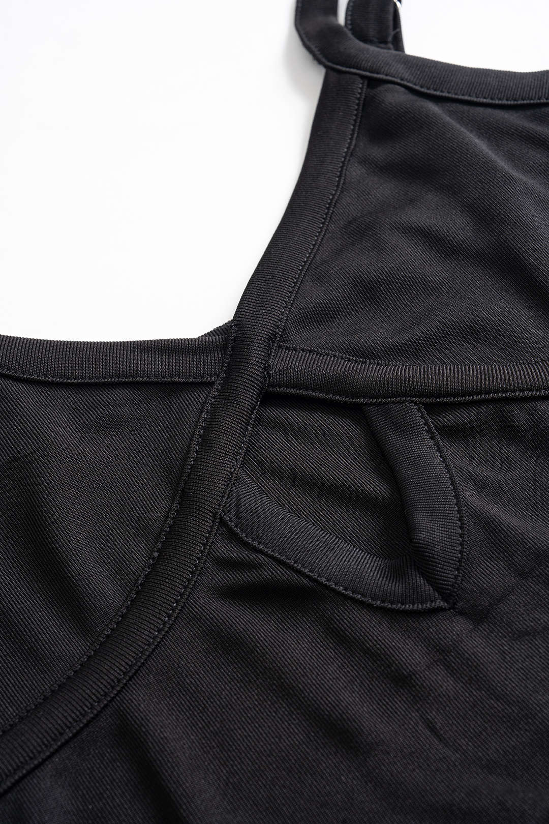 Close-up of the keyhole neckline and strap detail of a black dress.