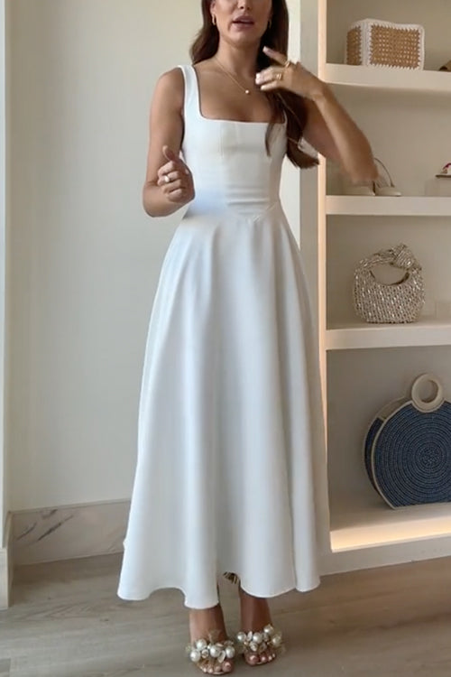A woman in a white square-neck midi dress and pearl-embellished heels.