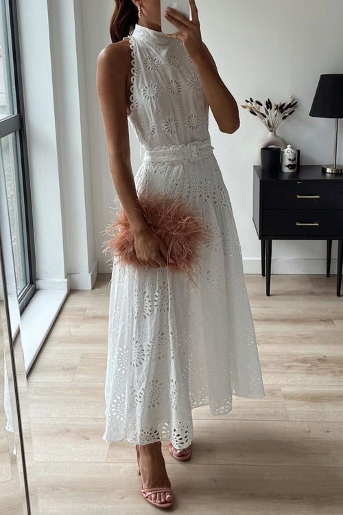 Woman in a white eyelet dress with a belted waist, holding a pink feather clutch
