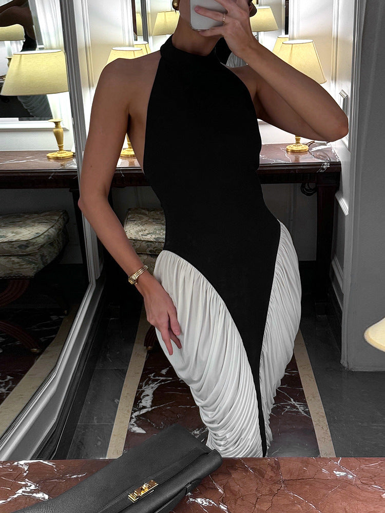 A woman in a black and white halter neck dress with ruched white fabric on the skirt, posing in a room with mirrors and lamps.