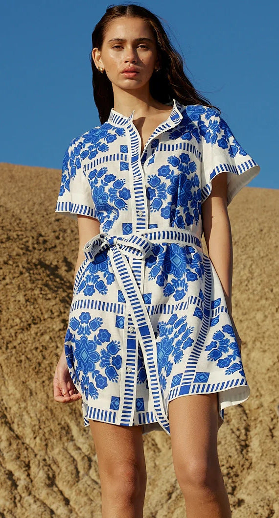 Close-up of a woman's torso in a white and blue floral print shirt dress with a belted waist.