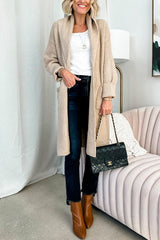 woman wearing a long beige knit cardigan over a white top and dark wash jeans