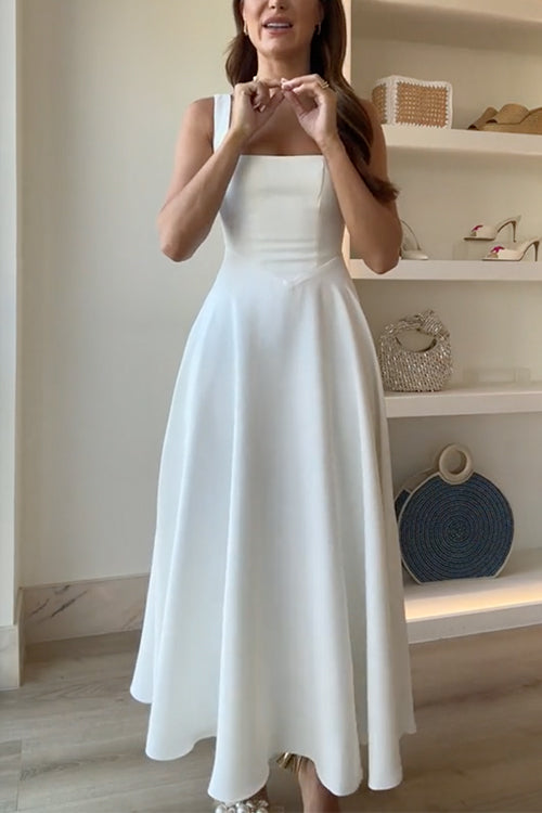A woman adjusts her necklace while wearing a white square-neck dress.
