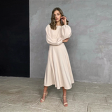 woman wearing a beige midi dress with bishop sleeves and an open back
