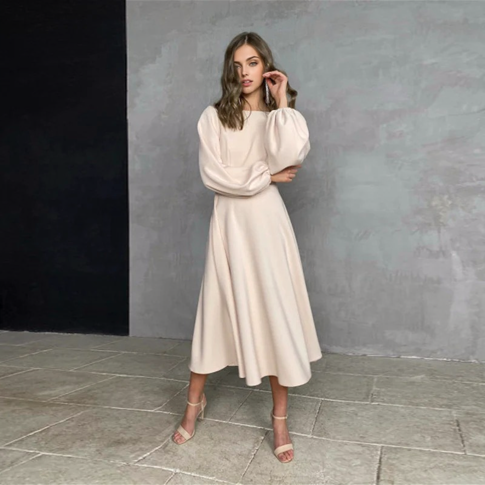 woman wearing a beige midi dress with bishop sleeves and an open back
