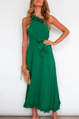 woman in green halter neck maxi dress with tie waist and ruffled hem, holding a clutch