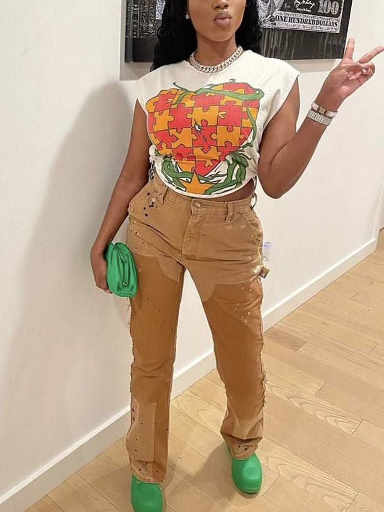 Full body shot of a woman in a white graphic t-shirt and brown distressed pants