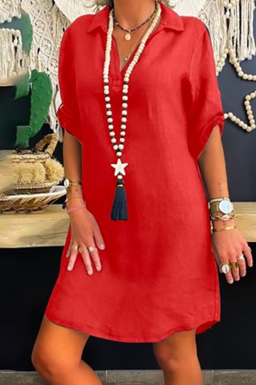 Woman wearing a red collared V-neck short sleeve A-line dress with a long beaded necklace with a star and tassel pendant.