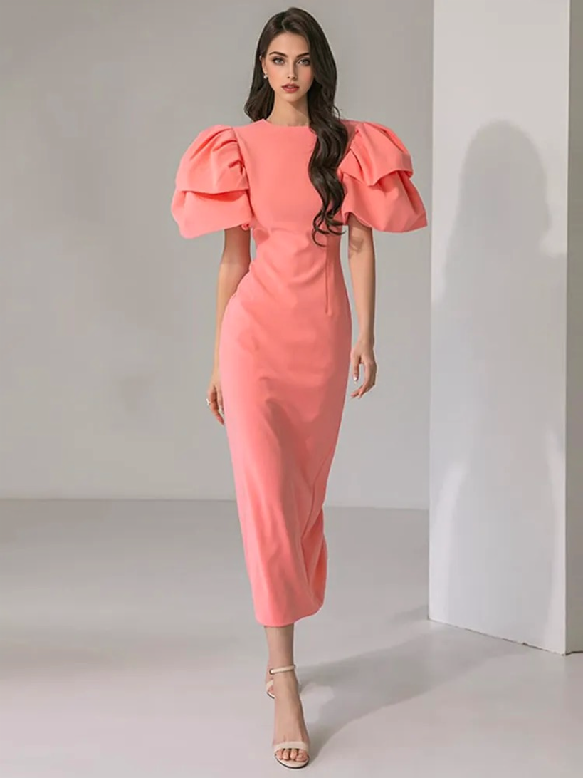 front view of a woman in a coral pink midi dress with dramatic puff sleeves