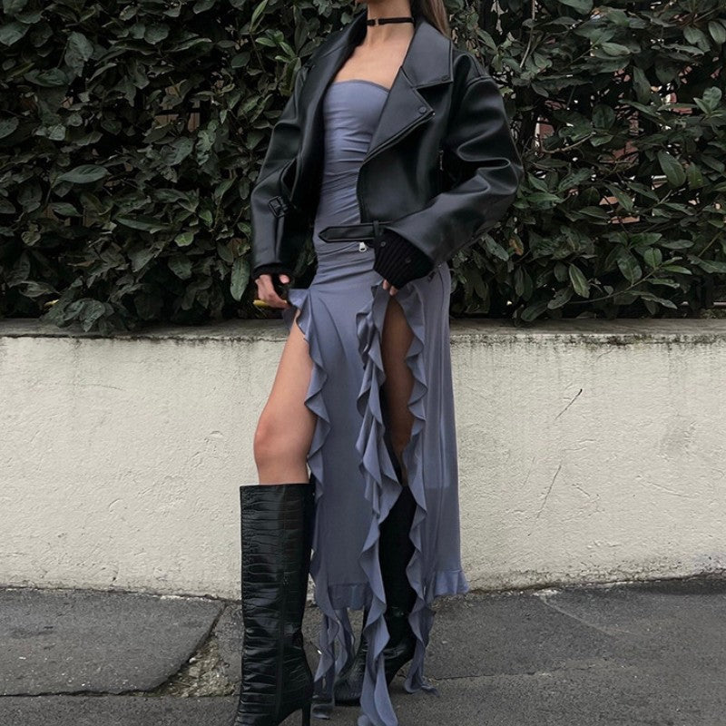Close-up of a woman wearing a slate gray strapless ruched dress with ruffled fringe and a black leather jacket.