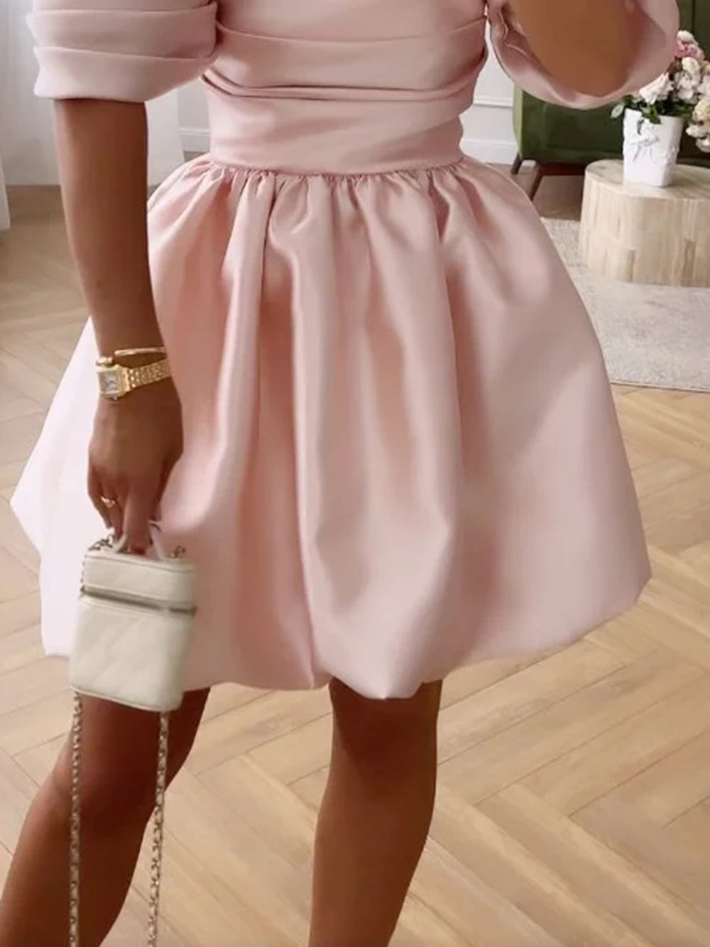 woman in a pink off-the-shoulder mini dress with a bubble skirt, holding a white clutch