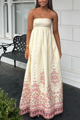 A woman wearing a cream strapless maxi dress with a pink floral print.