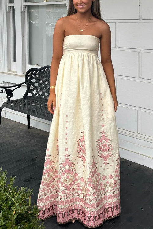 A woman wearing a cream strapless maxi dress with a pink floral print.