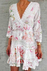 A woman modeling a white bohemian-style dress with colorful floral print and lace trim.