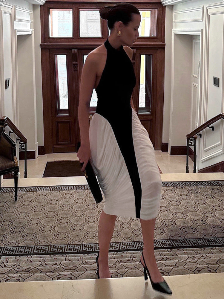 A woman in a black and white halter neck dress with ruched white fabric on the skirt, walking down a grand staircase.