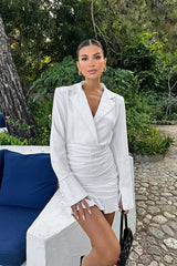 Close-up of a woman's upper body in a white ruched mini dress with a blazer collar.