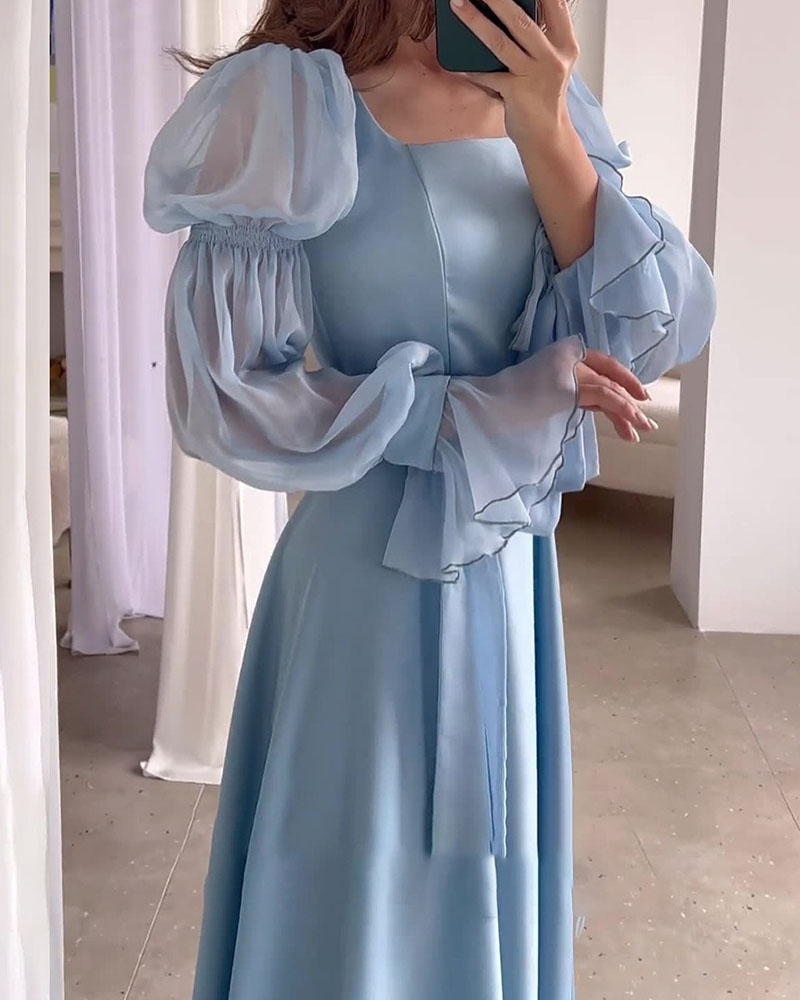 The woman turns slightly, showing the full length of the light blue a-line dress.