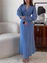 Woman wearing a long-sleeved blue dress with puffed sleeves and a V-neckline, standing in a room.