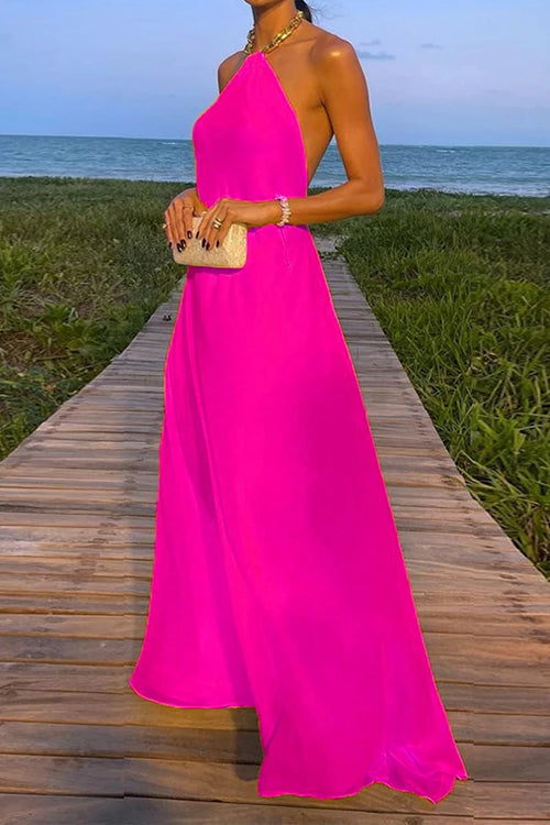 woman wearing a long pink halter neck dress with a flowy skirt on a boardwalk