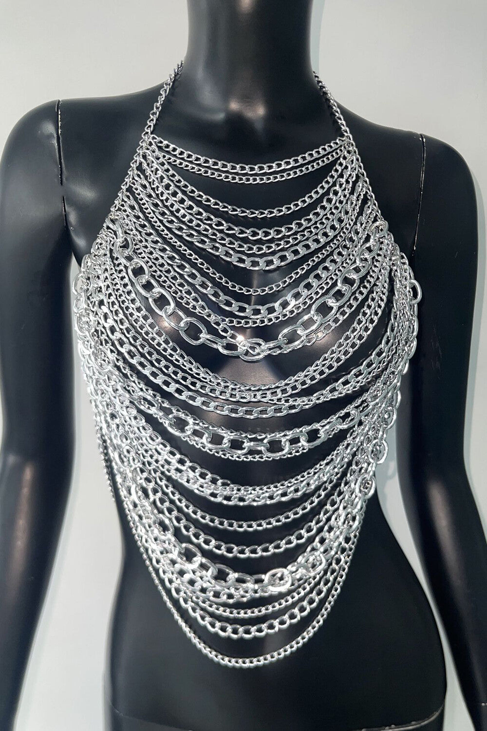 Silver chain halter top displayed on a black mannequin