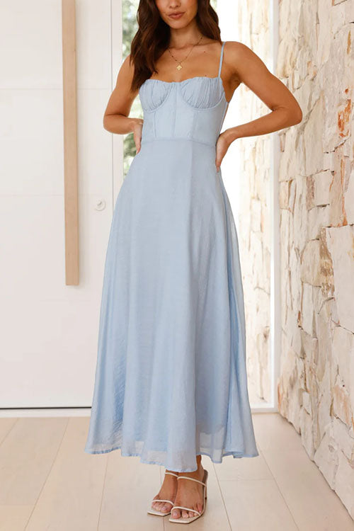 A woman in a light blue midi dress with her hands on her hips, showing the bodice detail.