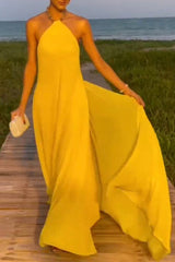woman wearing a long yellow halter neck dress with a flowy skirt on a boardwalk