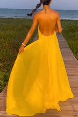 woman wearing a long yellow halter neck dress with an open back on a boardwalk