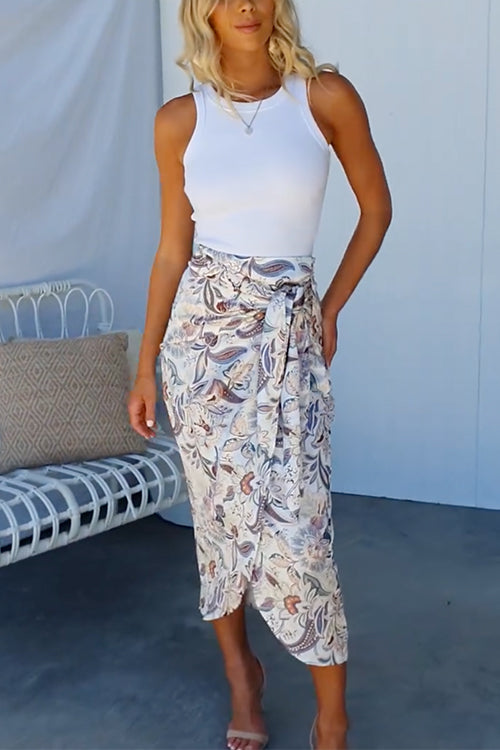 woman wearing a white tank top and a floral print midi wrap skirt
