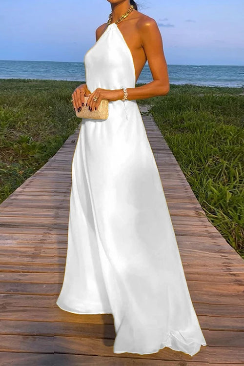 woman wearing a long white halter neck dress with a flowy skirt and a clutch on a boardwalk