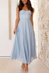 A woman smiling and modeling a light blue midi dress with a sweetheart neckline and spaghetti straps.