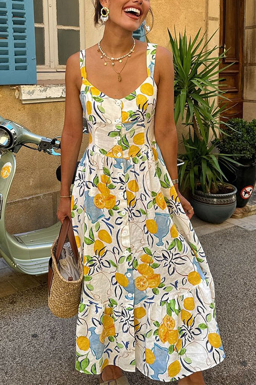 A woman smiling while wearing a lemon-print dress and jewelry.