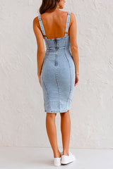 Rear view of a woman wearing a light blue denim sheath dress with a zipper closure and adjustable straps.