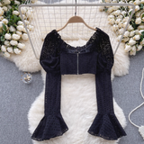 A black eyelet lace crop top with a zipper closure on the back, featuring puff sleeves and bell sleeves.