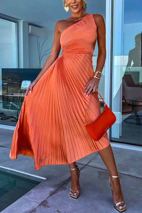 A woman in an orange one-shoulder pleated dress with a cut-out detail and a red handbag.