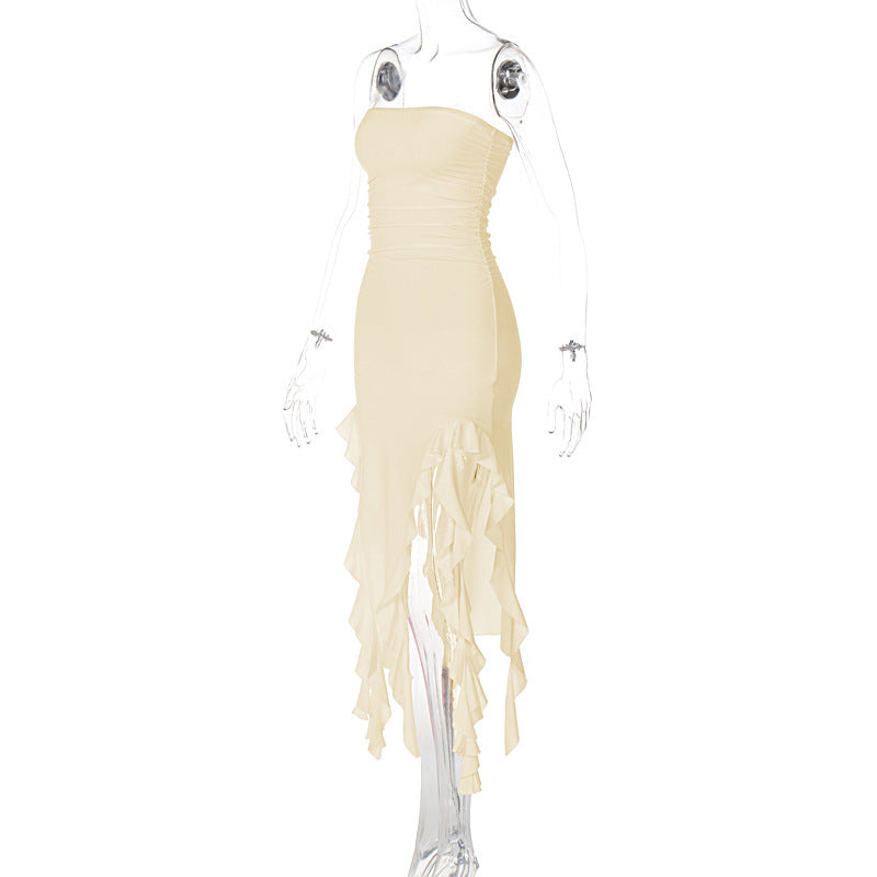 Side view of a cream strapless ruched midi dress with ruffled asymmetrical hemline and high slit on a mannequin.