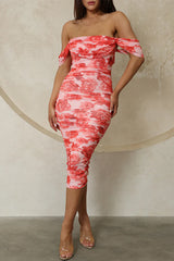Full-body shot of a woman wearing a red floral print, off-the-shoulder, ruched midi dress with clear heels.