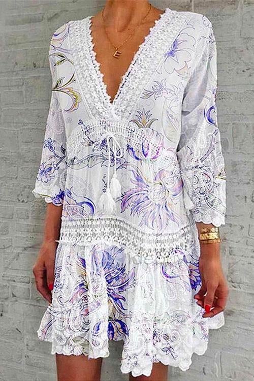 A woman modeling a white bohemian-style dress with purple floral print and lace trim.