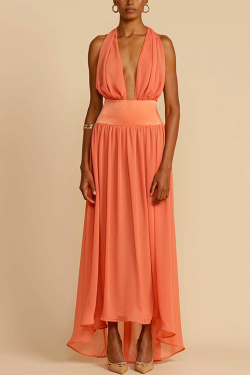 Model wearing a coral halter neck maxi dress with a deep V-neck and a flowing skirt, posed against a plain background.