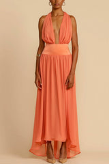Model wearing a coral halter neck maxi dress with a deep V-neck and a flowing skirt, posed against a plain background.