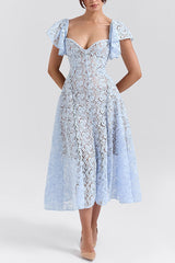 Woman standing in a light blue lace midi dress against a white background